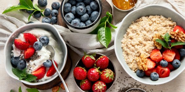 Healthy breakfast with oats, yogurt, strawberries, blueberries, and nuts.