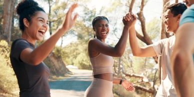 Friends enjoying a joyful outdoor workout high-five.