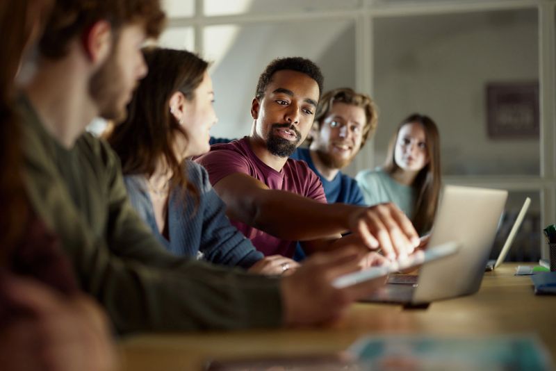 African American male freelancer and his colleague reading an e-mail on a computer during a meeting in the office.