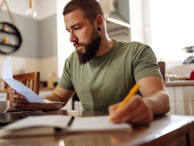 Bearded man reviewing documents at home.