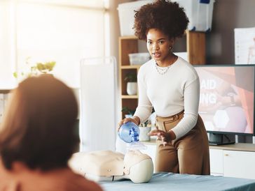 Woman demonstrating CPR on a training mannequin.