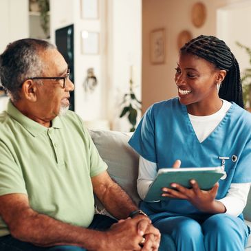 Nurse smiling and talking with elderly man at home.