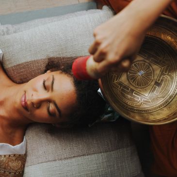 Woman receiving a sound therapy with a Tibetan singing bowl.