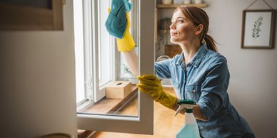 Woman cleaning a window with gloves and a cloth.