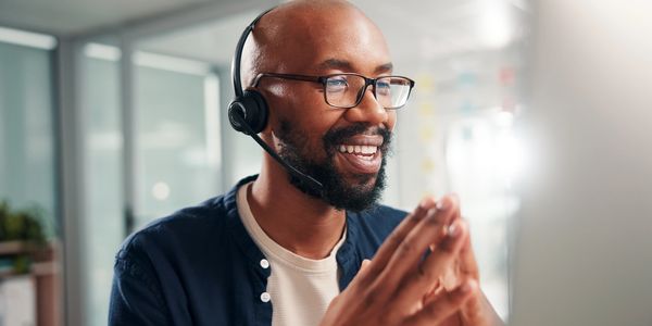 Smiling man with headset engaged in a video call.