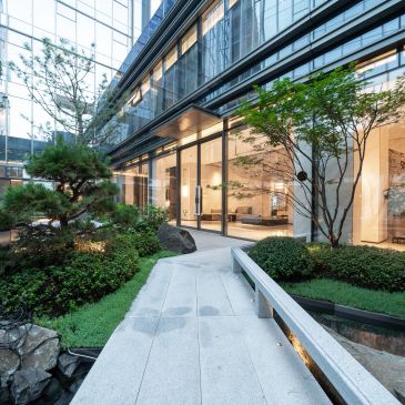 Modern building with garden and glass walls.