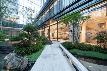 Modern courtyard with greenery and glass building.
