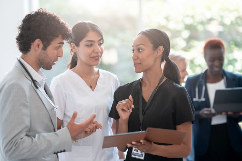 Group of healthcare professionals collaborating in a bright medical facility, emphasizing teamwork and communication to ensure optimal patient care outcomes.