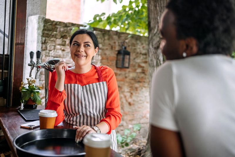 Taking a coffee break together while working at coffee shop standing in front of bar counter