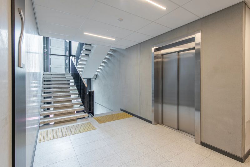 Bright interior of a contemporary building featuring stairs, elevator, and minimal architecture design with clean finishes.