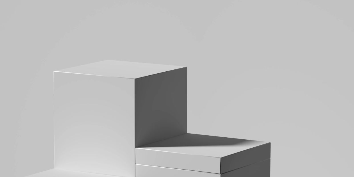Two stacked white rectangular blocks casting soft shadows on a plain gray surface.