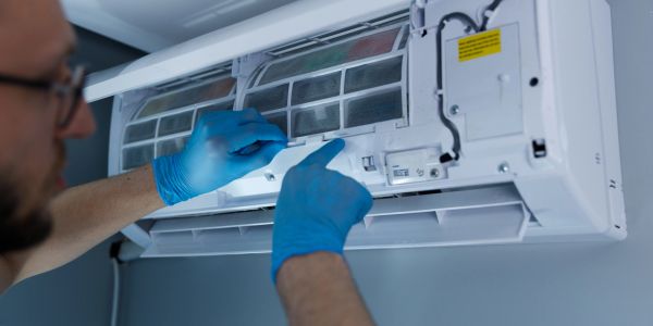 Technician maintaining an air conditioner wearing gloves.