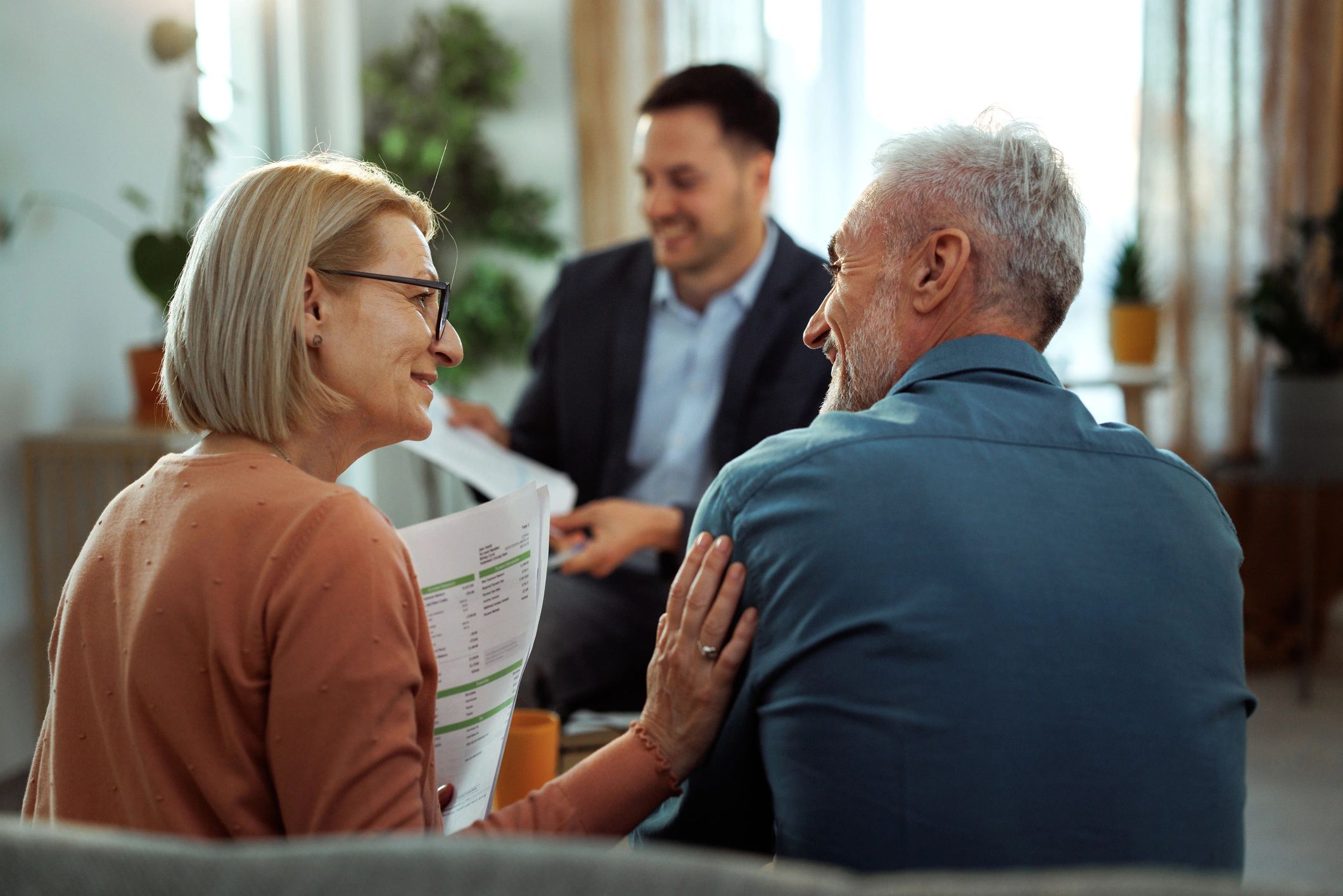 Happy elderly couple consulting with a professional over coffee.