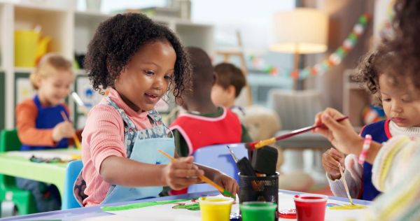 Children painting at a table in a classroom.