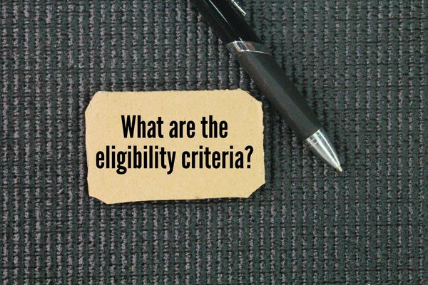 Note card asking about eligibility criteria with a pen.