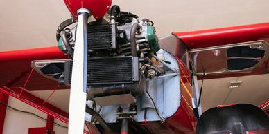 Close-up of a red airplane's propeller and engine inside a hangar.