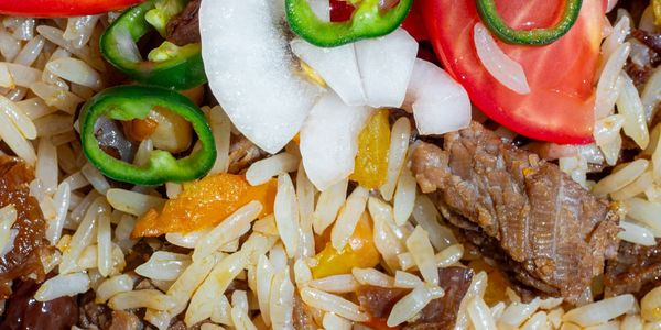 Close-up of rice dish with beef, jalapeños, onions, and tomatoes.