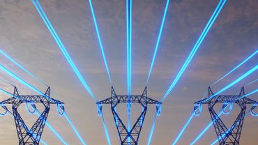 Electric pylons with blue laser-like beams against a cloudy sky.