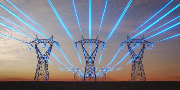 Electricity transmission towers glowing with blue energy lines at dusk.