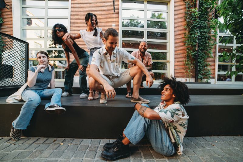 Group of diverse young adults enjoying their time together, chatting and laughing on a bench in the city