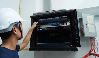 Techniker überprüft Netzwerkanschlüsse in einem Serverschrank.