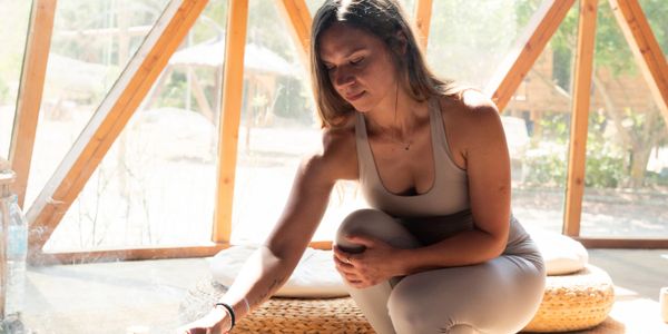 Person meditating in tranquil indoor space with candle.