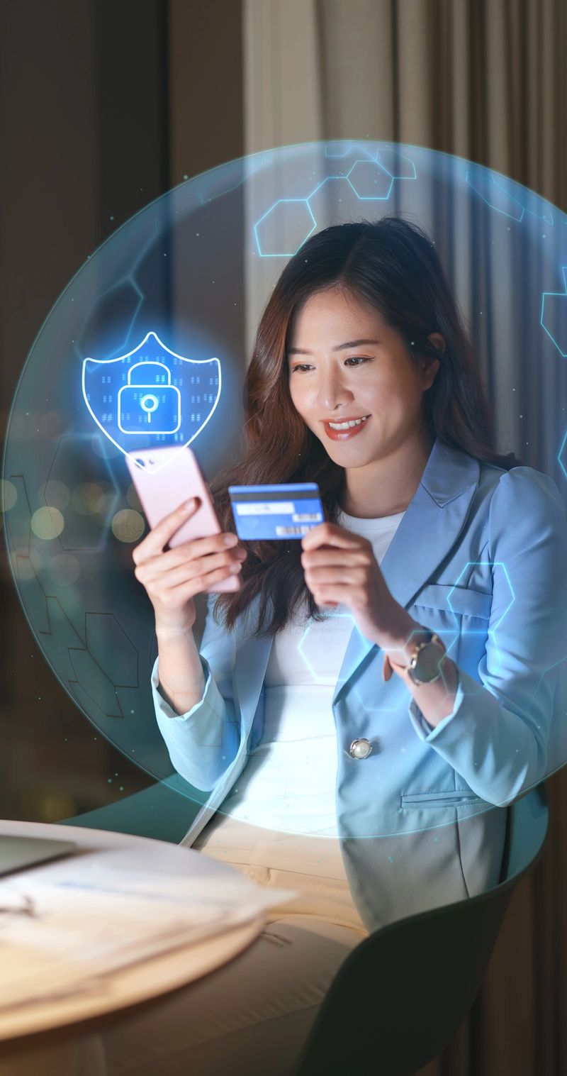 Circle of Protection - asian woman holds smartphone and credit card protected by virtual security shield at night
