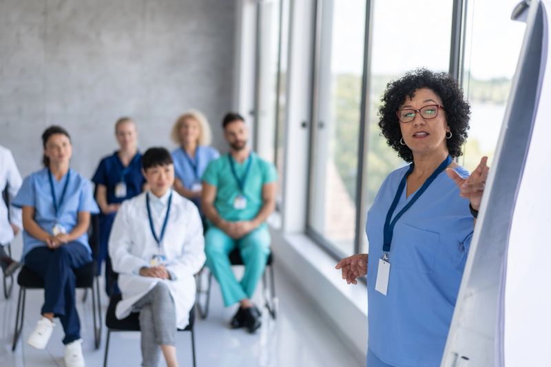 A healthcare professional leads a presentation, illustrating effective communication and teamwork during a training session with medical staff.