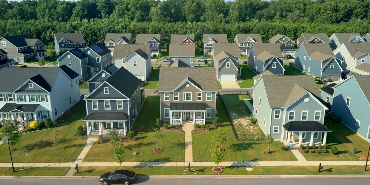 Aerial view of a suburban neighborhood with modern houses and manicured lawns.