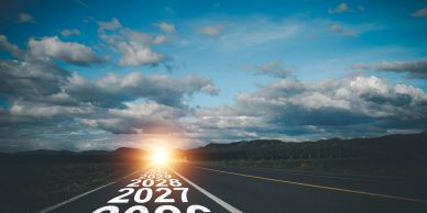 Road with years marked, leading to a bright sunrise on the horizon.
