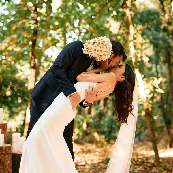 Bride and groom share a romantic kiss during an outdoor wedding.