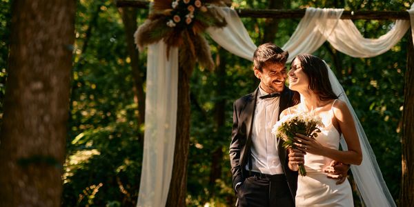 A joyful bride and groom embrace during their outdoor wedding ceremony.