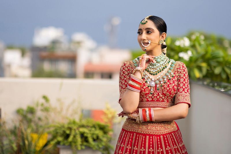 Portrait of very beautiful young Indian bride in luxurious bridal costume with makeup and heavy jewellery outdoors