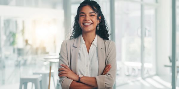 Mujer sonriente con brazos cruzados en oficina.