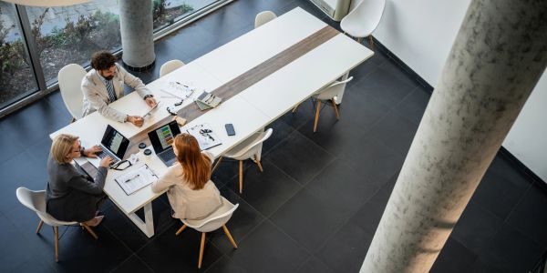 Three people collaborate around a large table in a modern office.
