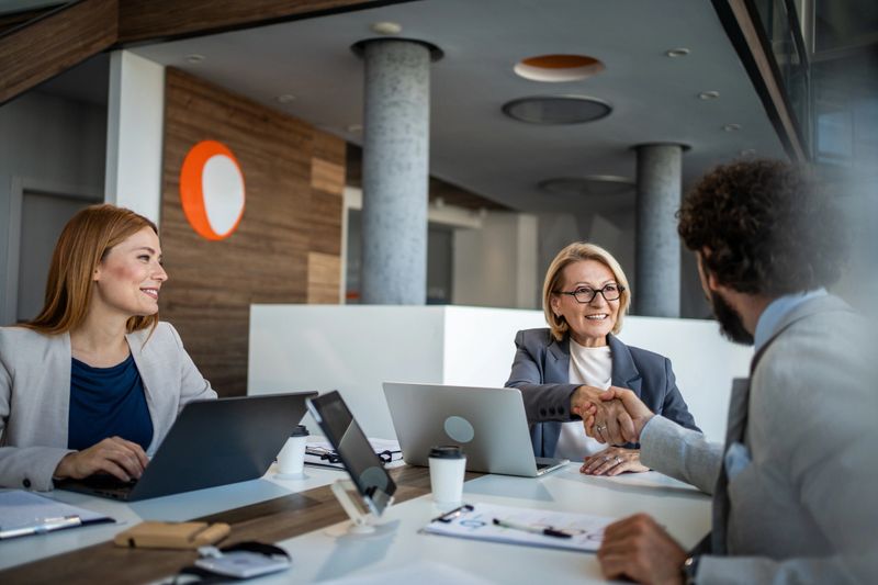 Business partners shaking hands in a modern office, celebrating a successful meeting and solidifying their agreement. Smiling faces reflect confidence and teamwork in this professional environment