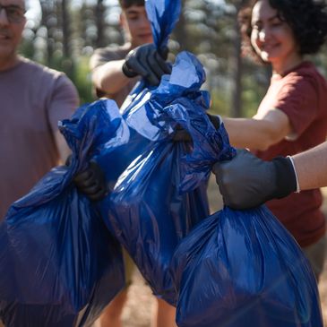People holding blue garbage bags, likely after a cleanup activity outdoors.