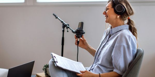 Woman recording a podcast with headphones and microphone.