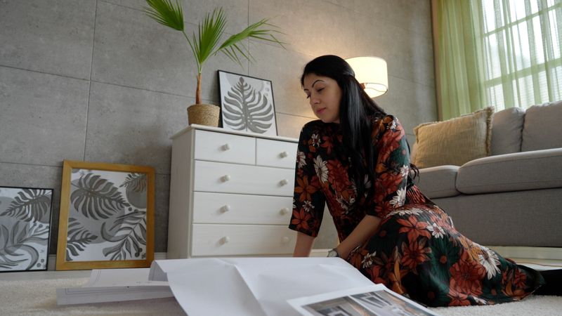 Real estate agent prepares property documents for sale contract while sitting on rug in stylish modern living room full of greenery. Concept of buy or sell home
