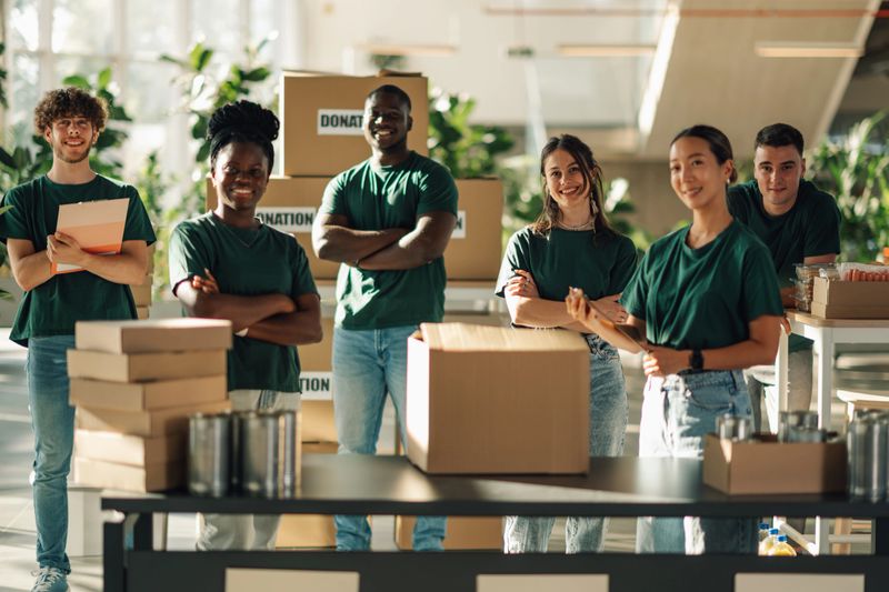 Group of diverse volunteers sorting food and other donations, working together to support those in need and foster community unity