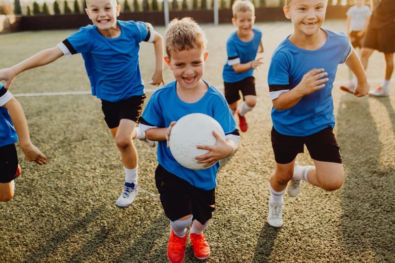 Group of cheerful boys running while playing soccer on a sports field
