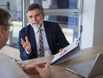 Two businessmen in a discussion with charts in an office setting.