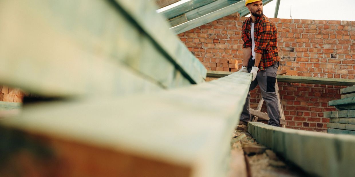 Construction worker carrying a wooden plank.