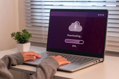 Person downloading files on a laptop at 80%.