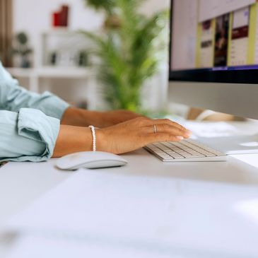 Person typing on a keyboard at a clean desk with a computer and mouse.