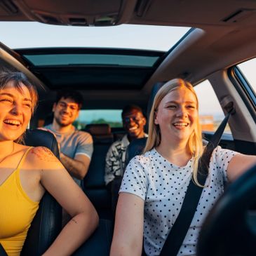 Four friends happily driving and enjoying a car ride.