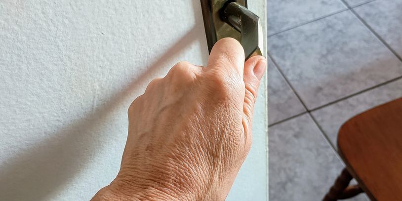 Hand gripping a door handle to open a door indoors.