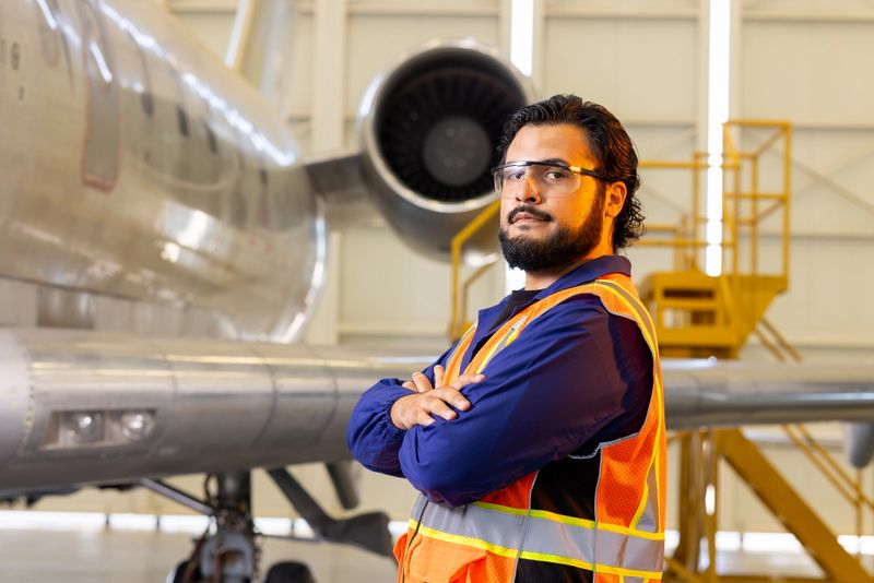 Tech man inspecting the outside of the plane's fuselage.