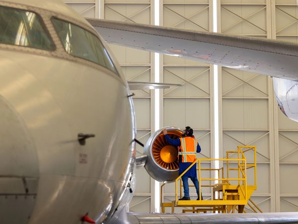 Technician inspects airplane engine in hangar.
