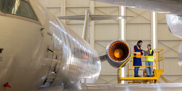 Two aviation technicians inspecting a jet engine in a hangar.